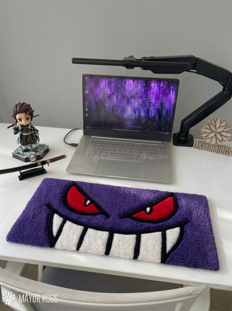 Gengar inspired Pokémon hand-tufted keyboard rug featuring a purple ghost character face with red eyes, oversized white teeth, and bold black detailing for anime gaming and desk décor by Mayur Rugs.