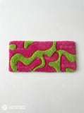 Hot pink and lime green abstract hand-tufted keyboard rug with flowing raised shapes displayed on a modern desk setup by Mayur Rugs.