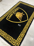 Black rug with gold border and logo on a white tiled floor