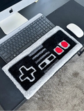Desk setup with a retro gaming controller-shaped mat, keyboard, mouse, and computer monitor.