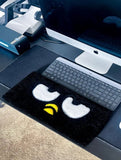 Black rug with cartoon face design on a desk with computer setup