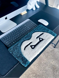 Desk setup with a keyboard, mouse, and decorative rug featuring a face design.