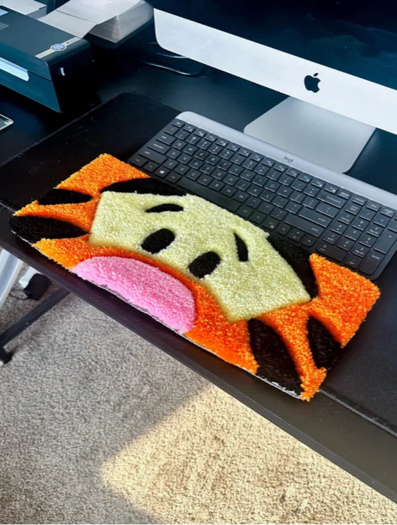 Colorful fish-shaped rug on a desk with a computer setup
