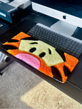 Colorful fish-shaped rug on a desk with a computer setup