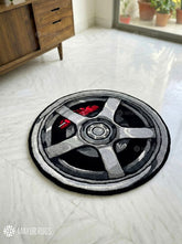Round rug with a wheel design on a light-colored floor, branded 'Mayur Rugs'.