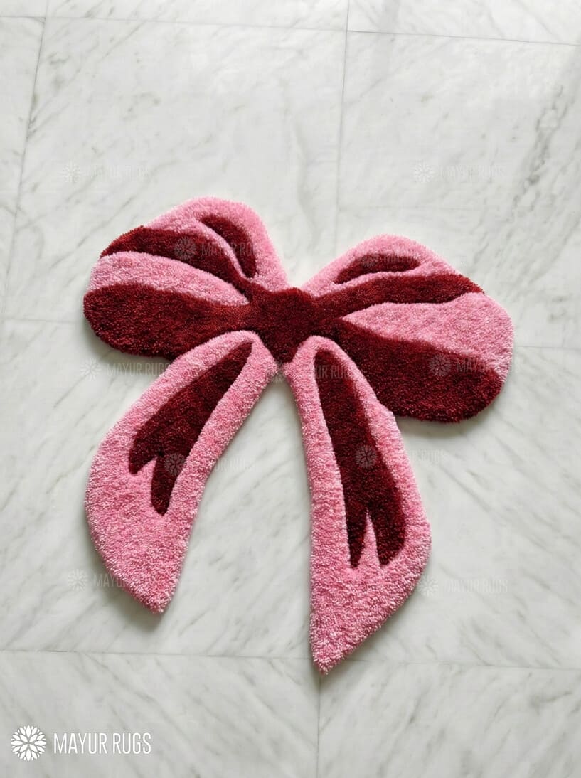 Pink bow-shaped rug on a light gray textured surface