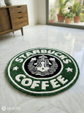 Starbucks Coffee rug on a light-colored floor with a wooden cabinet and plants in the background.