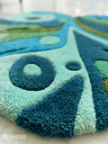 Blue monstera leaf hand tufted wool rug featuring tropical botanical artwork by Mayur Rugs