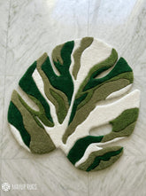 Green monstera leaf shaped hand tufted wool rug featuring layered botanical patterns by Mayur Rugs