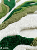 Green monstera leaf shaped hand tufted wool rug featuring layered botanical patterns by Mayur Rugs