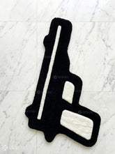 Black gun-shaped rug on a white textured surface