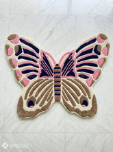 Butterfly-shaped rug with pink and brown colors on a white background