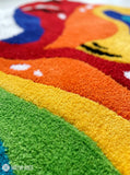 Rainbow paint spill hand tufted wool wall art rug featuring a colorful tipped paint bucket and flowing rainbow design by Mayur Rugs.