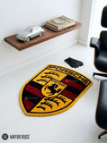 Porsche crest inspired hand-tufted custom wool rug featuring a detailed shield emblem, horse crest, Stuttgart lettering, and red, black, gold, and white automotive design by Mayur Rugs.
