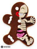 Gingerbread-shaped custom hand-tufted rug featuring a cream skeleton illustration, brown body, pink anatomical details, and red accents by Mayur Rugs.