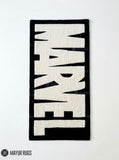 Marvel inspired hand-tufted wool area rug featuring oversized cream-white comic book lettering on a deep red background for superhero and pop-culture décor by Mayur Rugs.
