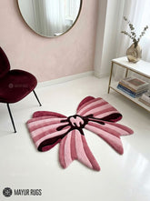 Pink ribbon bow 3D hand-tufted custom wool rug featuring layered blush, rose, dusty pink, and burgundy ribbon shapes with a sculpted center knot for coquette and feminine décor by Mayur Rugs.