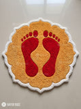 Diwali rangoli-inspired hand-tufted custom wool rug featuring red Lakshmi Charan-inspired footprints on a golden-yellow base with a scalloped ivory-white border by Mayur Rugs.