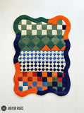 Multicolor hand-tufted abstract area rug featuring geometric checkerboard, diamond, and colorblock patterns in green, blue, orange, rust red, and ivory with wavy edges by Mayur Rugs.