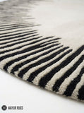 Round ivory area rug with radiating black sunburst lines in varied lengths, creating a bold minimalist monochrome design by Mayur Rugs.