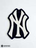 New York Yankees inspired hand-tufted custom wool rug featuring a cream interlocking NY baseball logo on a black background by Mayur Rugs.