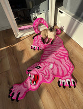 Cat playing on a pink panther-shaped rug indoors