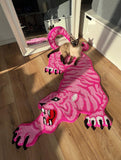 Cat playing on a pink panther-shaped rug indoors