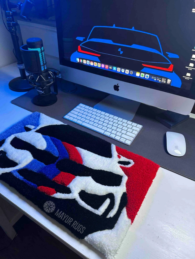 Computer desk setup with a rug featuring a car design on a desk.