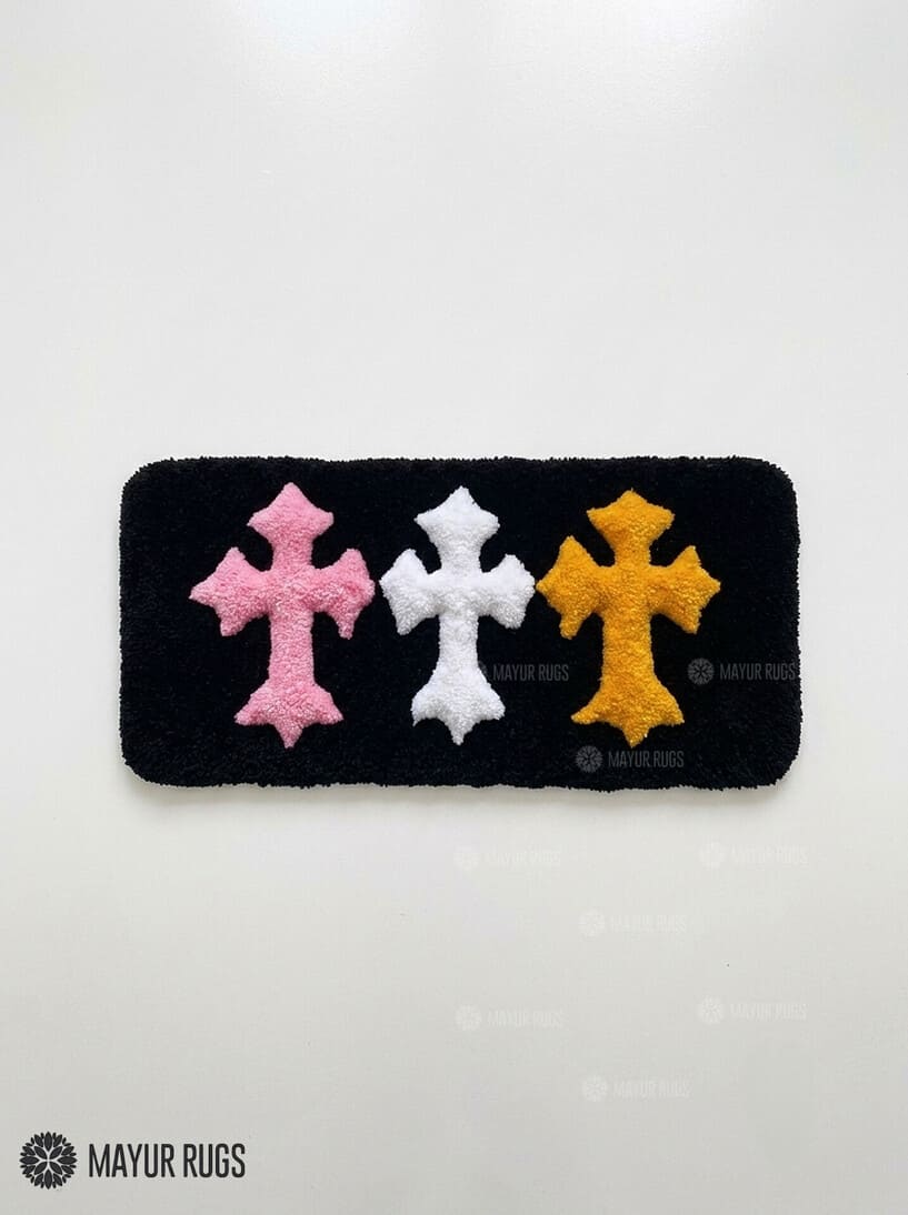 Chrome Hearts inspired cross keyboard rug featuring raised pink, white, and yellow gothic crosses on a black hand-tufted wool desk rug by Mayur Rugs.