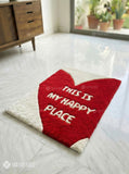 Heart-shaped red rug with 'This is my happy place' text on a light wooden floor.