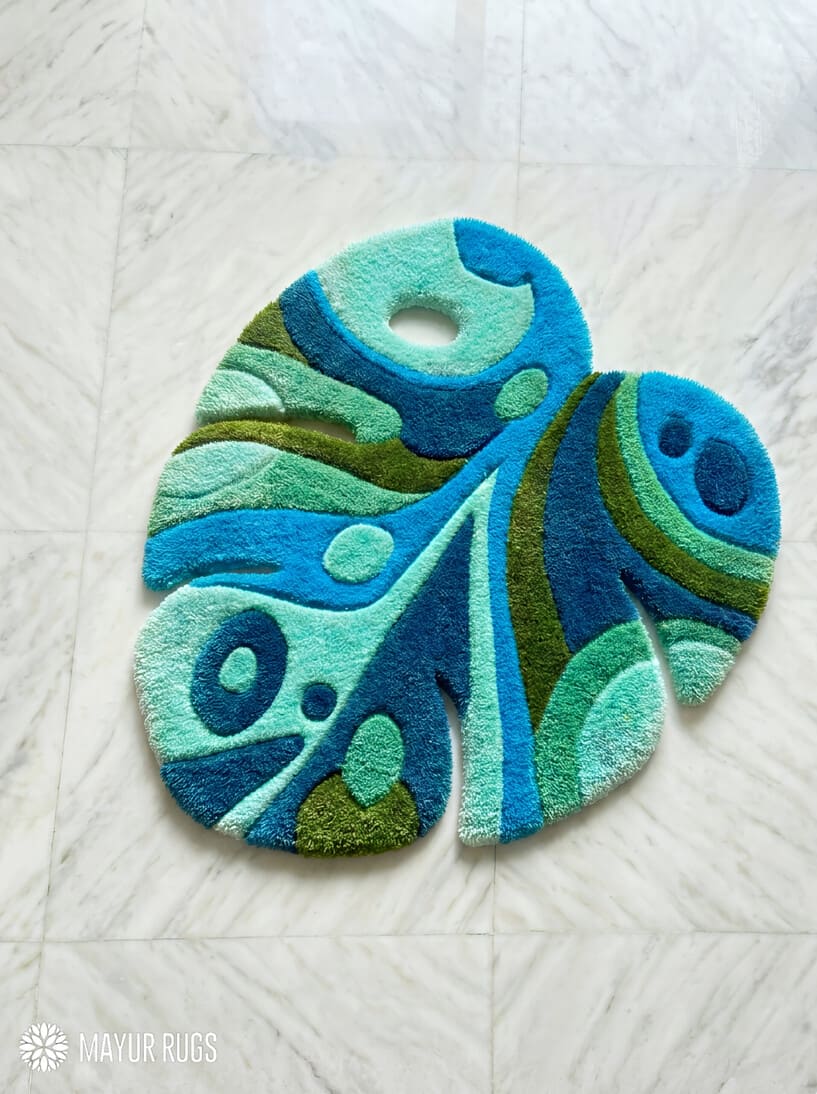 Blue monstera leaf hand tufted wool rug featuring tropical botanical artwork by Mayur Rugs