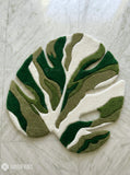 Green monstera leaf shaped hand tufted wool rug featuring layered botanical patterns by Mayur Rugs