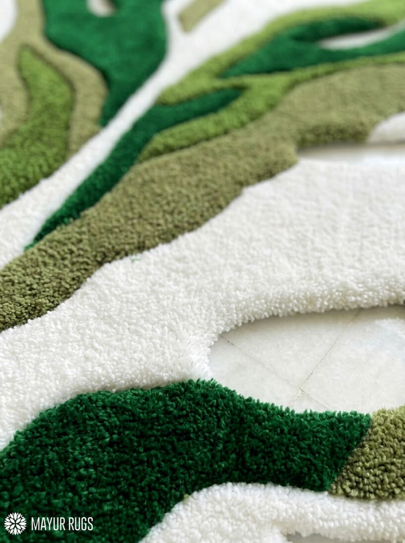 Green monstera leaf shaped hand tufted wool rug featuring layered botanical patterns by Mayur Rugs