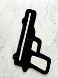 Black gun-shaped rug on a white textured surface
