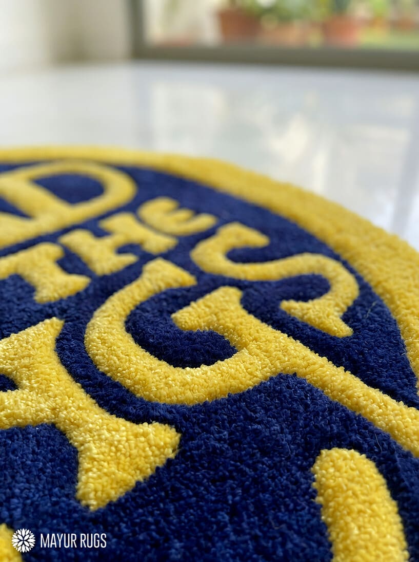Close-up of a blue and yellow rug LOTR typography round hand-tufted wool rug with fantasy cinematic aesthetic design by Mayur Rugs