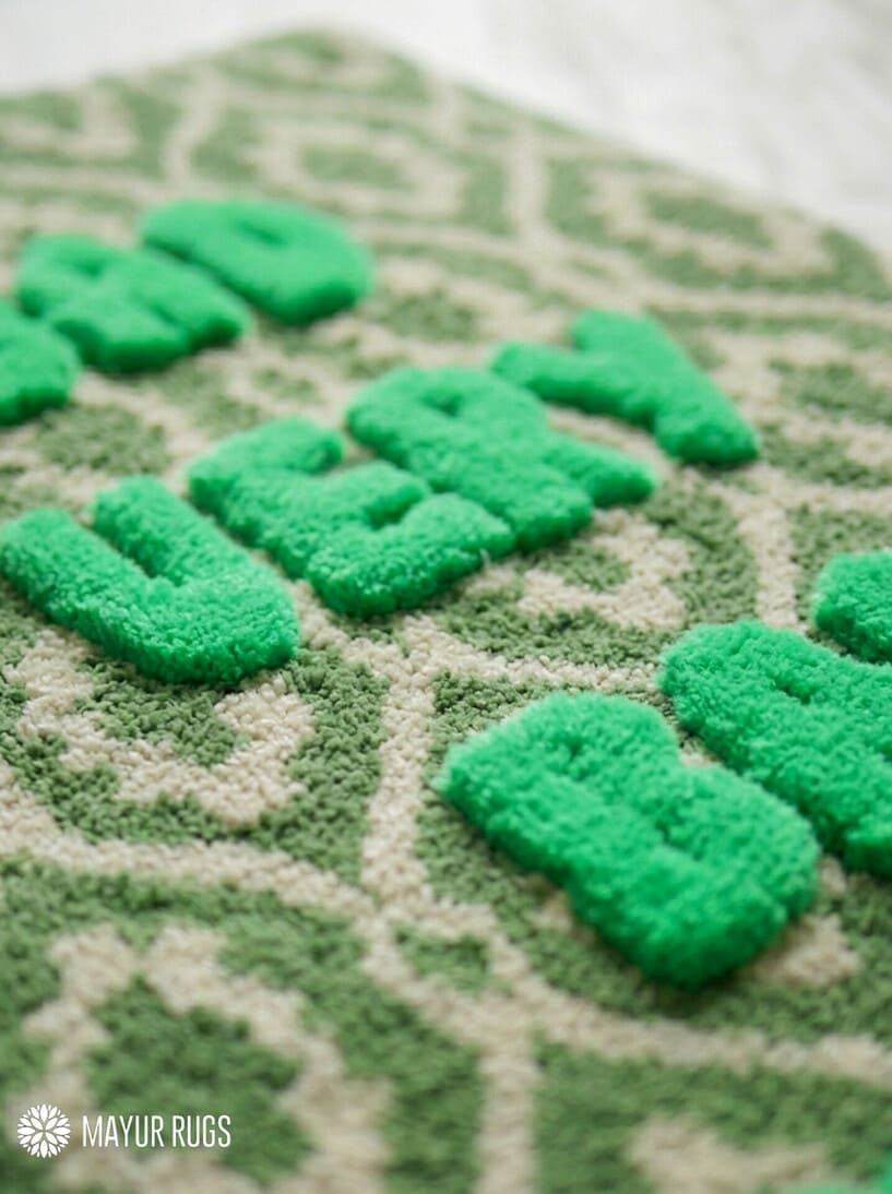 Green and cream hand tufted loop and cut rug featuring raised Bad Very Bad Bitch typography by Mayur Rugs