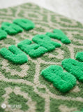 Green and cream hand tufted loop and cut rug featuring raised Bad Very Bad Bitch typography by Mayur Rugs