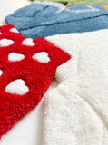 Dirty laundry hand-tufted custom wool rug featuring a colorful pile of clothes, shorts, socks, and garments in green, blue, white, beige, and red with raised 3D detailing by Mayur Rugs.