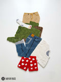 Dirty laundry hand-tufted custom wool rug featuring a colorful pile of clothes, shorts, socks, and garments in green, blue, white, beige, and red with raised 3D detailing by Mayur Rugs.