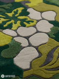 Abstract botanical camo hand-tufted wool area rug featuring layered green organic leaf and floral shapes in olive, moss, lime, beige, and charcoal by Mayur Rugs.