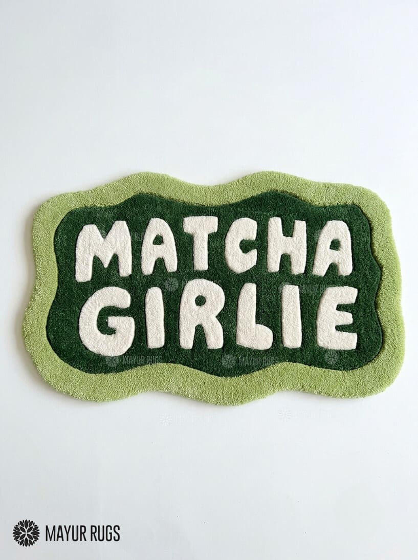 Matcha Girlie hand-tufted custom wool rug featuring cream typography on a dark green center with a wavy light green border by Mayur Rugs.