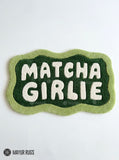 Matcha Girlie hand-tufted custom wool rug featuring cream typography on a dark green center with a wavy light green border by Mayur Rugs.