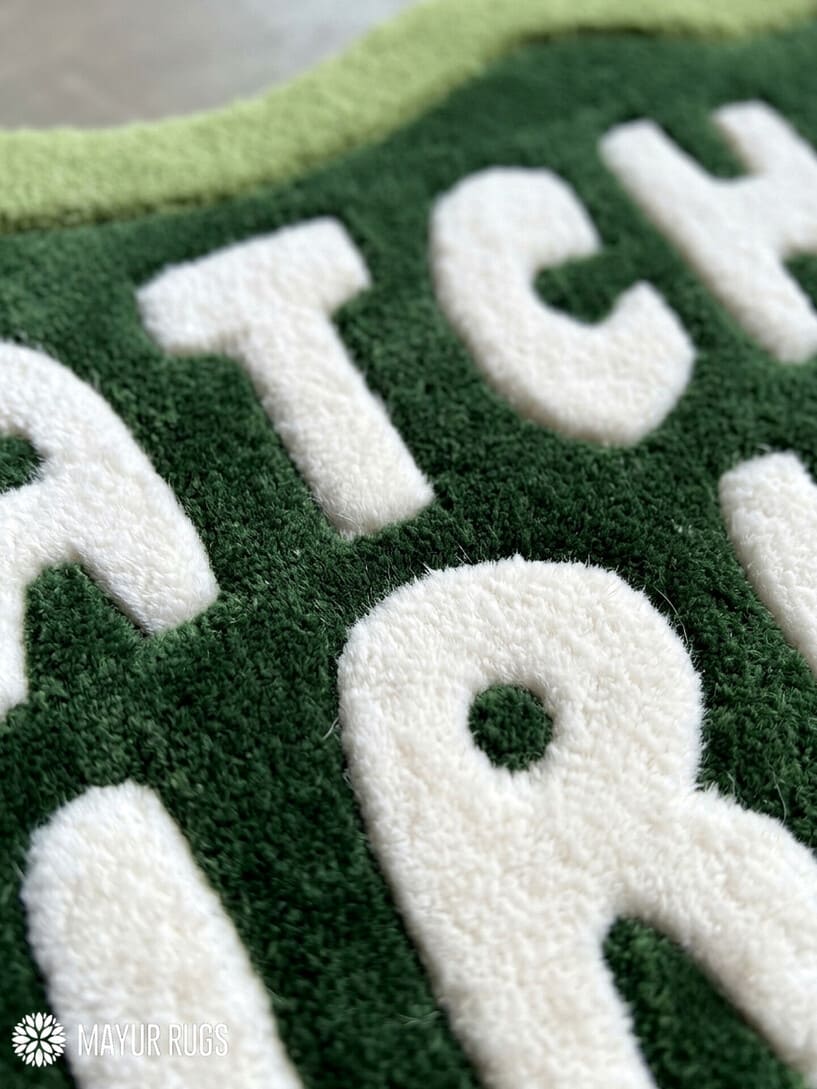 Matcha Girlie hand-tufted custom wool rug featuring cream typography on a dark green center with a wavy light green border by Mayur Rugs.