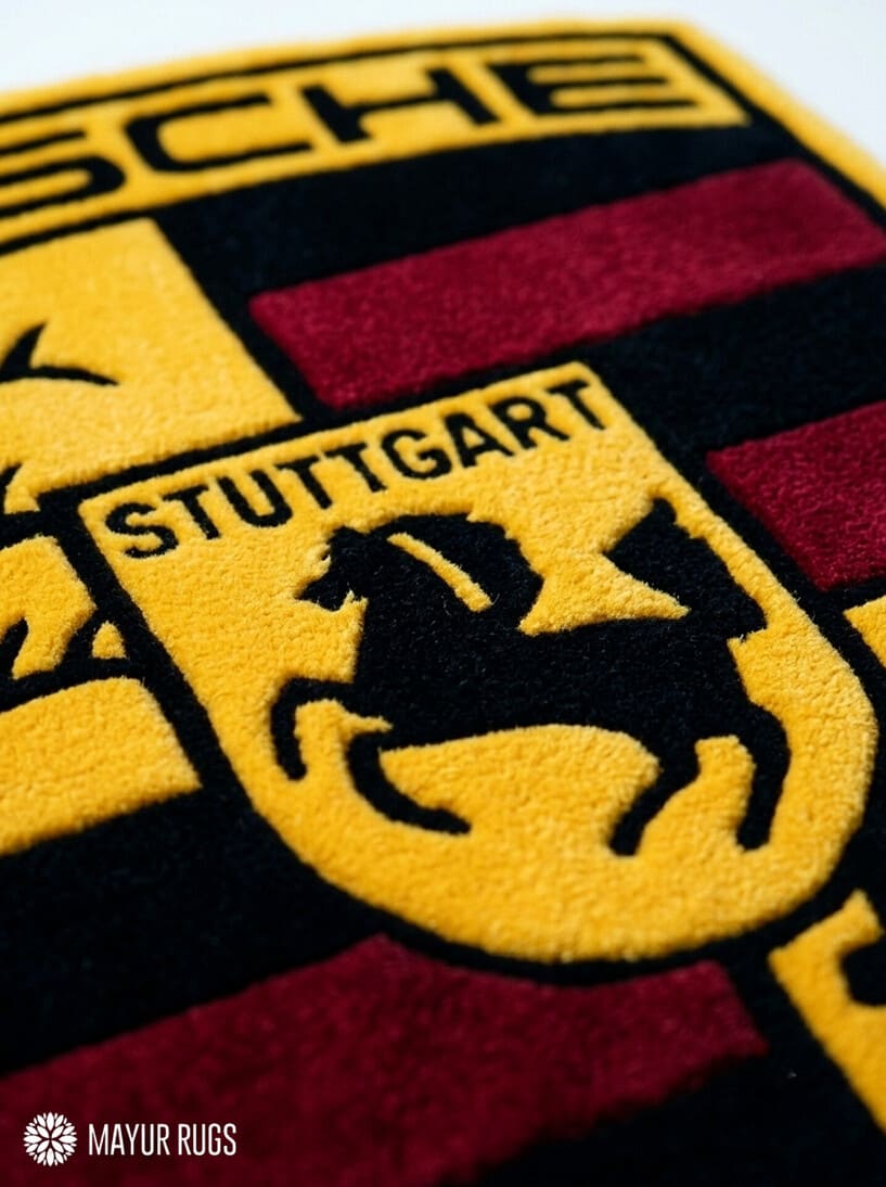Porsche crest inspired hand-tufted custom wool rug featuring a detailed shield emblem, horse crest, Stuttgart lettering, and red, black, gold, and white automotive design by Mayur Rugs.
