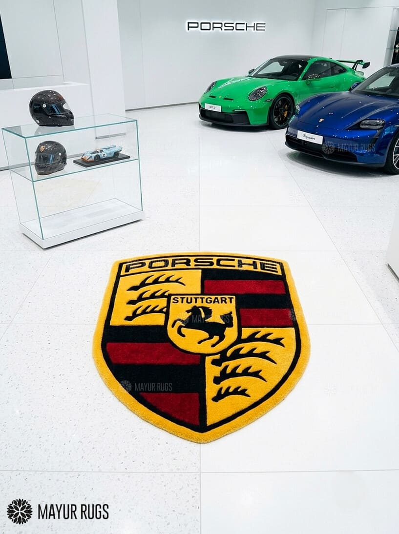 Porsche crest inspired hand-tufted custom wool rug featuring a detailed shield emblem, horse crest, Stuttgart lettering, and red, black, gold, and white automotive design by Mayur Rugs.