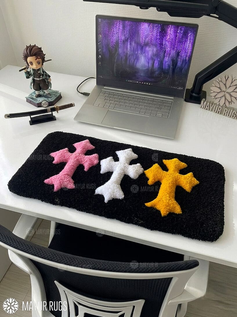 Chrome Hearts inspired cross keyboard rug featuring raised pink, white, and yellow gothic crosses on a black hand-tufted wool desk rug by Mayur Rugs.