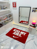Kiss My Airs inspired hand-tufted wool rug featuring bold white typography and a swoosh-style graphic on a red background for sneakerhead and streetwear décor by Mayur Rugs.