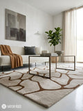 A large area rug with an organic, wavy abstract pattern in brown and cream, styled in a modern living room setting with a sofa, coffee table, and potted plant.