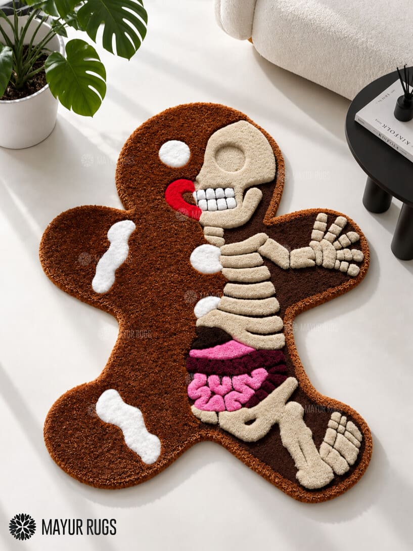 Gingerbread-shaped custom hand-tufted rug featuring a cream skeleton illustration, brown body, pink anatomical details, and red accents by Mayur Rugs.