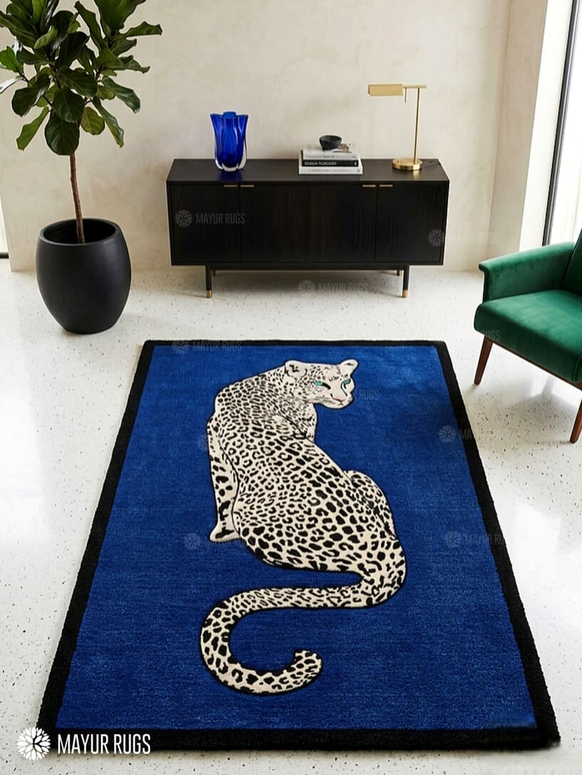 Rectangular hand-tufted leopard rug featuring a cream and black spotted leopard with turquoise eyes on a royal blue background and black border by Mayur Rugs.